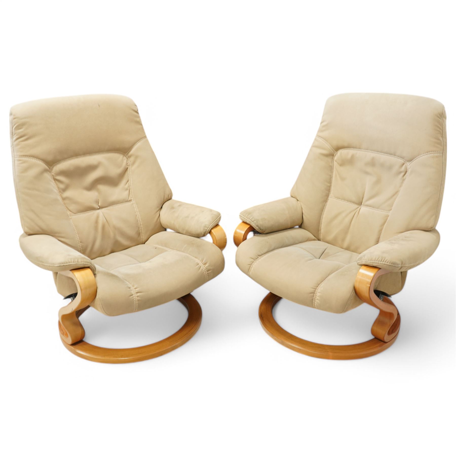 Himolla - A pair of swivel reclining chairs, beige upholstered with padded arms and high back rest, raised on a laminated circular wooden base with swivel mechanism 
