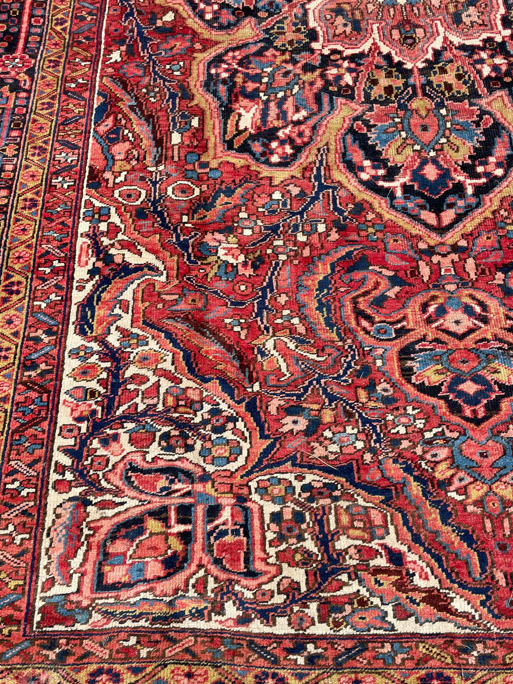Antique Persian coral ground carpet, the large central floral pole medallion with extending foliate designs, the thick guarded indigo border with repeating flower heads and circles