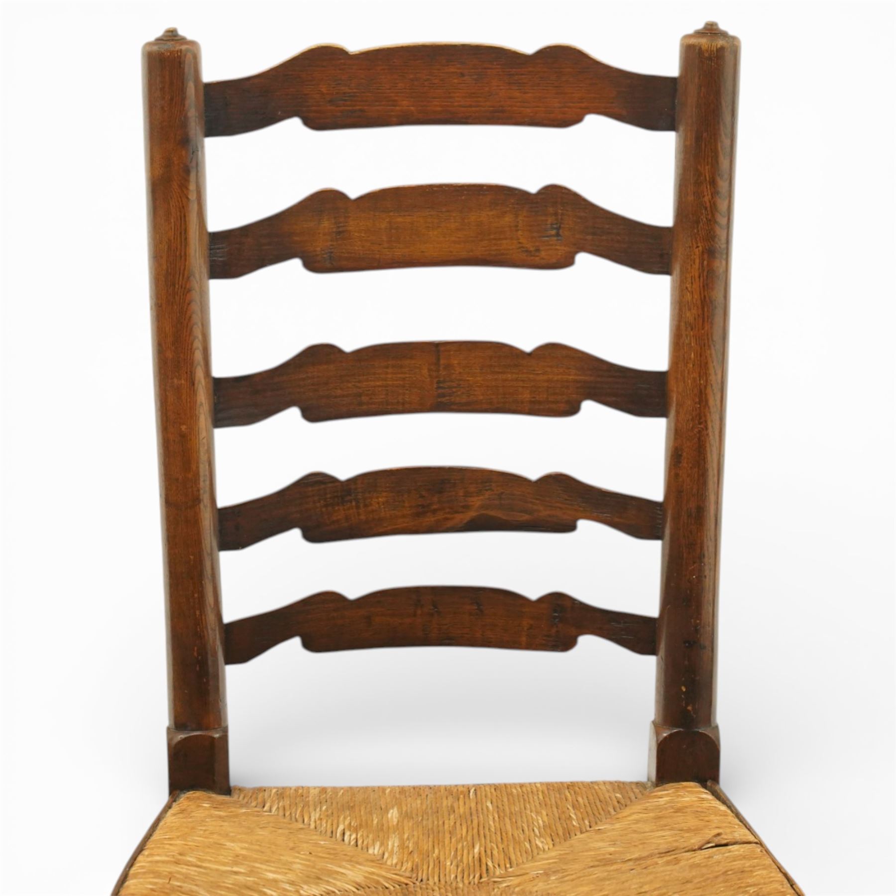 Early 19th century set of six country ladder back chairs, each with five shaped horizontal slats, woven rush seats within square frames, standing on turned forelegs united by peripheral stretchers with turned front rail