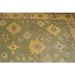 Lage Turkish Oushak green ground carpet, the field decorated with large stylised plant motifs and geometric design, the sage green guard band with further repeating foliate motifs