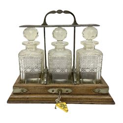  Edwardian oak tantalus with silver plated locking mechanism and three square sided glass decanters, complete with key, H32cm