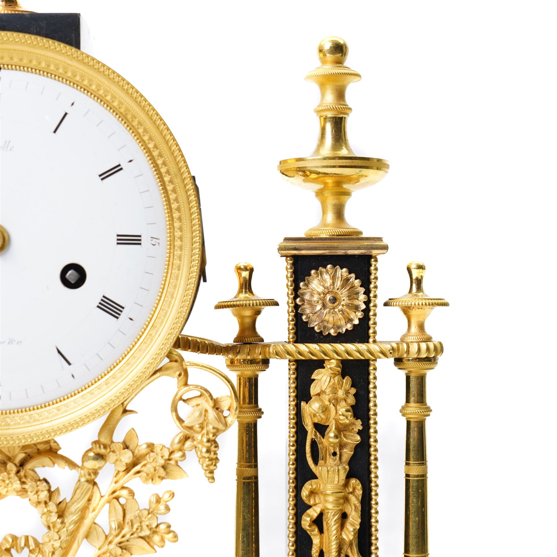 French-Early 19th century 8-day ormolu and polished black slate portico clock, case surmounted with a twin handled urn with flowers, supported by two square pedestals with finials and trailing floral mounts on oval bases, raised on an oval plinth with toupie feet, enamel dial signed 