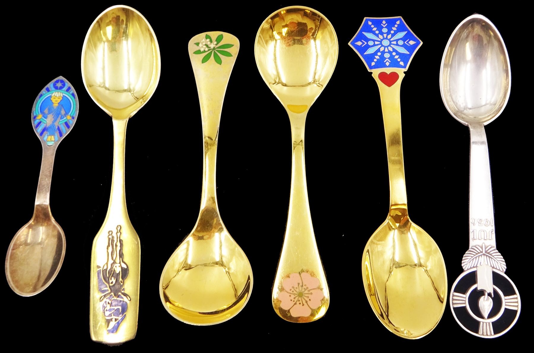 Six Danish silver and silver-gilt year spoons, including four example by Anton Michelsen, each with enamel decoration, including Christmas and other religious designs, dated between 1936 and 1984, each with maker's stamps to underside, together with two silver-gilt examples by Georg Jensen, each with enamel flowers to finials, dated 1975 and 1976, with maker's mark and Sterling Denmark stamped to underside 