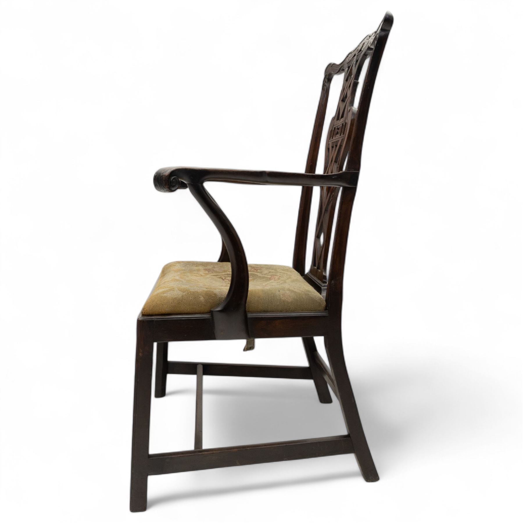 19th-century Chippendale Revival design mahogany oversized high-back armchair, serpentine crest carved top rail above pierced back splat with interlaced ribbon carving and geometric fretwork design, and outward scrolling arms above drop-in needlework seat on square chamfered legs 