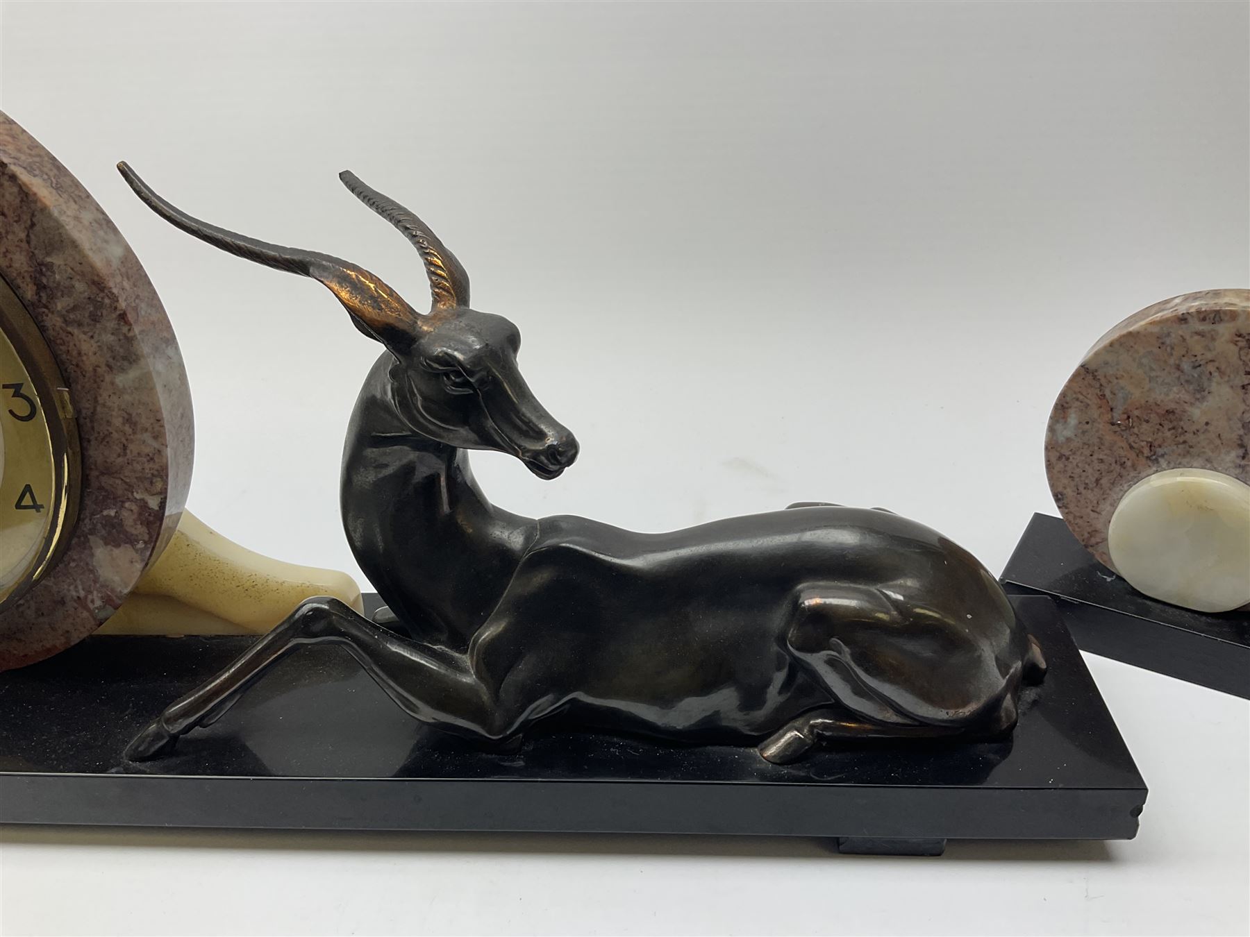 Art Deco style marble and anodised spelter three-piece clock garniture, model with recumbent gazelle, centre piece L52cm.  