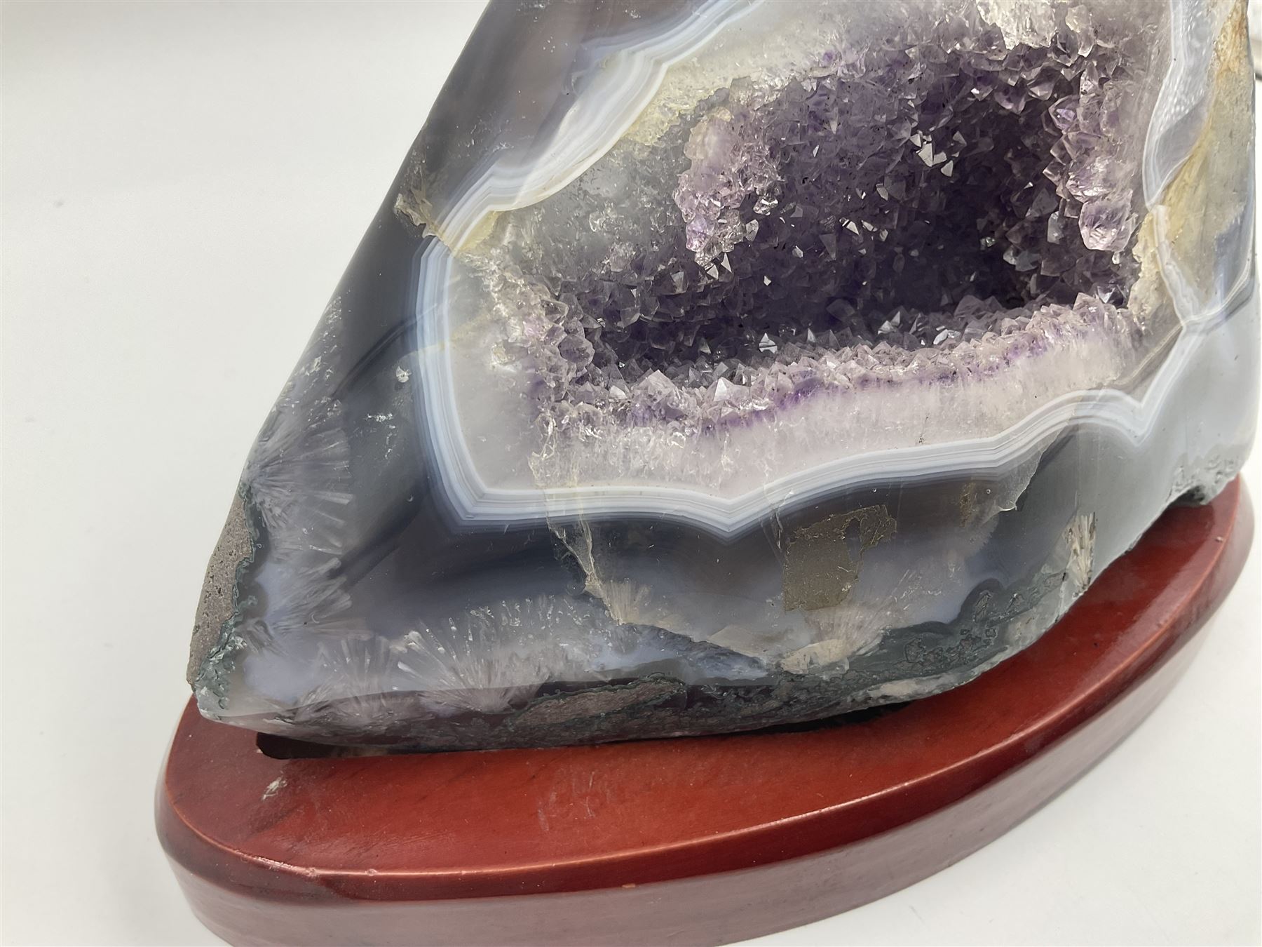 Amethyst crystal geode cluster, with well-defined crystals of various sizes, upon a carved wooden stand, H12cm, L20cm
