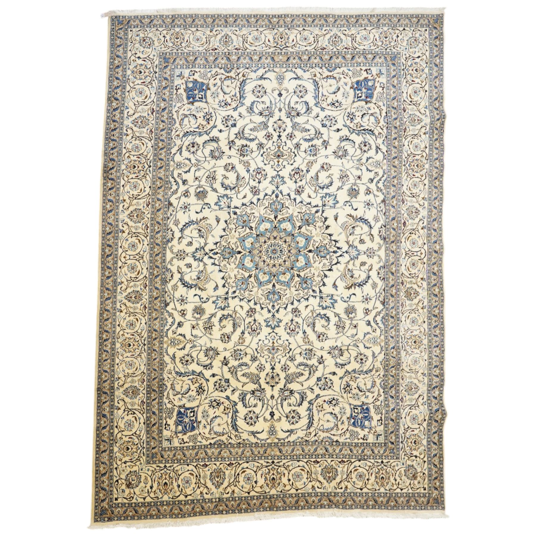 Central Persian Nain hand-knotted carpet, ivory field with central radiating medallion, issuing an all-over design of scrolling vines, palmettes, and delicate floral sprays with conforming spandrels, enclosed by a foliate border, framed by multiple guard stripes, with cotton fringe ends 
