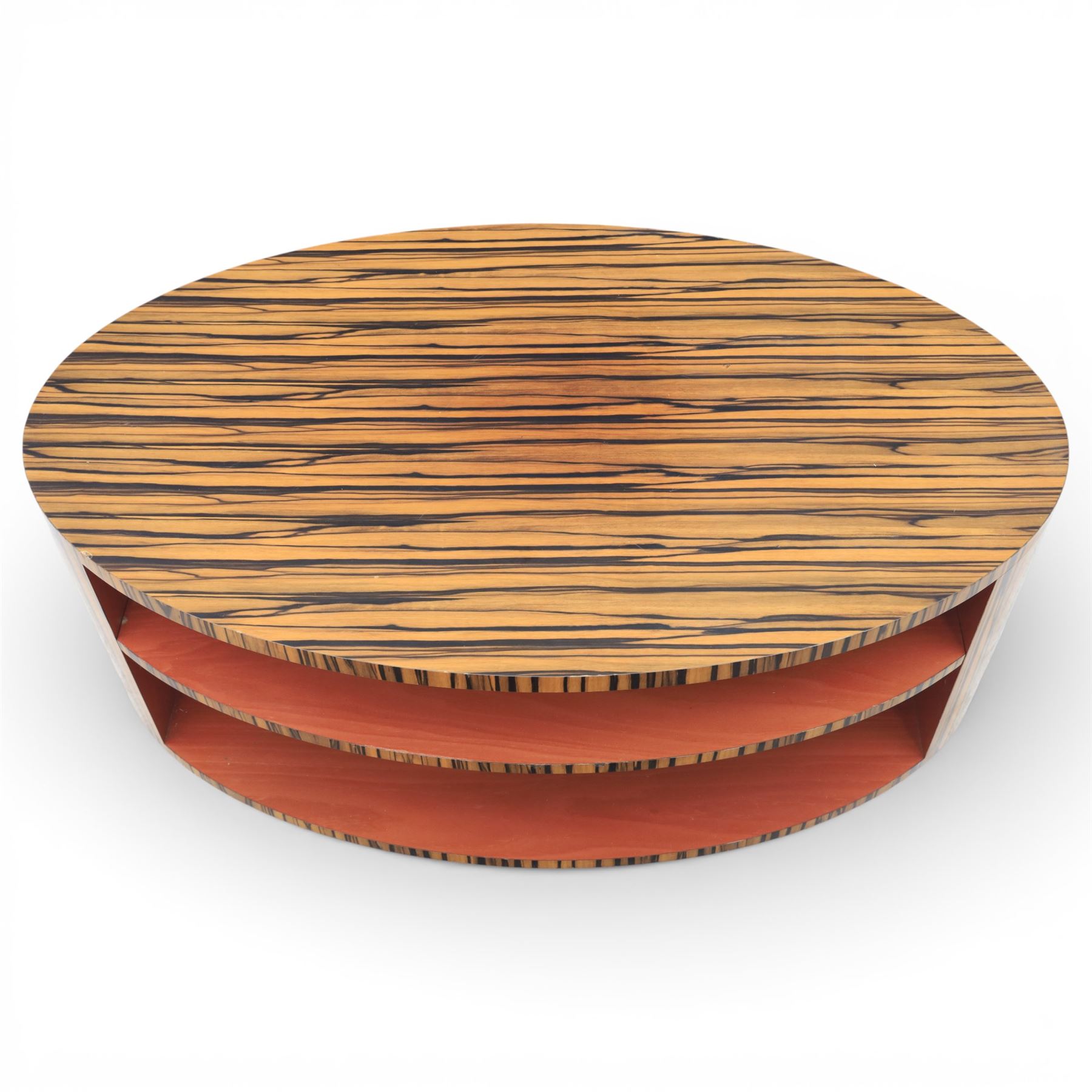 Toby Winteringham - Mid 20th century zebra wood coffee table, oval top with book matched striped veneers over two open tiers painted red, the curved end supports and continuous plinth base veneered to match, recessed plinth base 