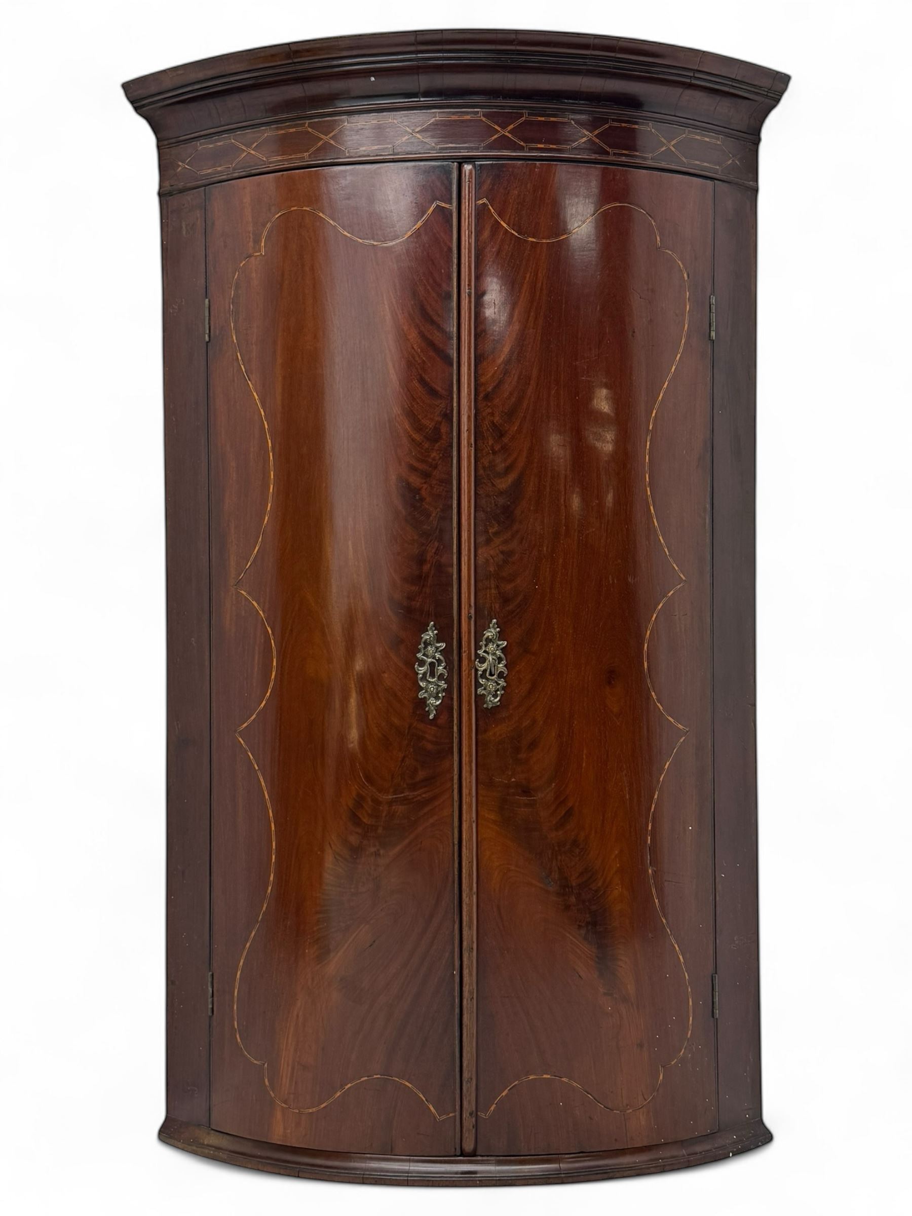 Late Georgian mahogany hanging corner cupboard, moulded cornice with interlaced boxwood stringing pattern above two cupboard doors inlaid with wave form boxwood stringing and four internal shelves 