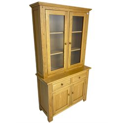 Contemporary light oak bookcase display cabinet, fitted with  two glazed doors enclosing two shelves, above two drawers and cupboards
