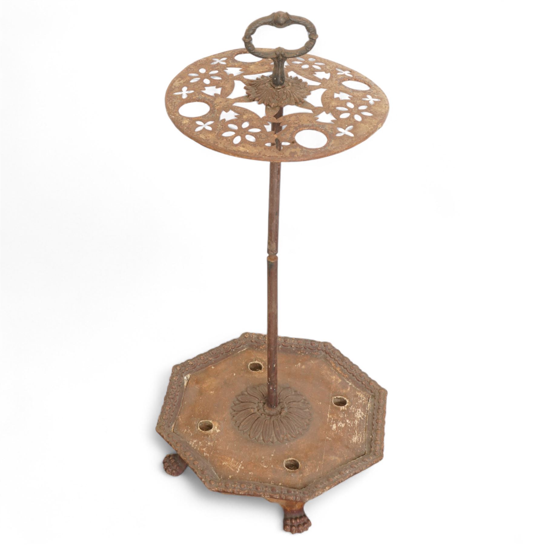 Victorian cast iron cane or stick stand, the top with a large loop lifting handle and floral design above geometric pierced decoration, central vertical rod, and octagonal base with lion paw feet