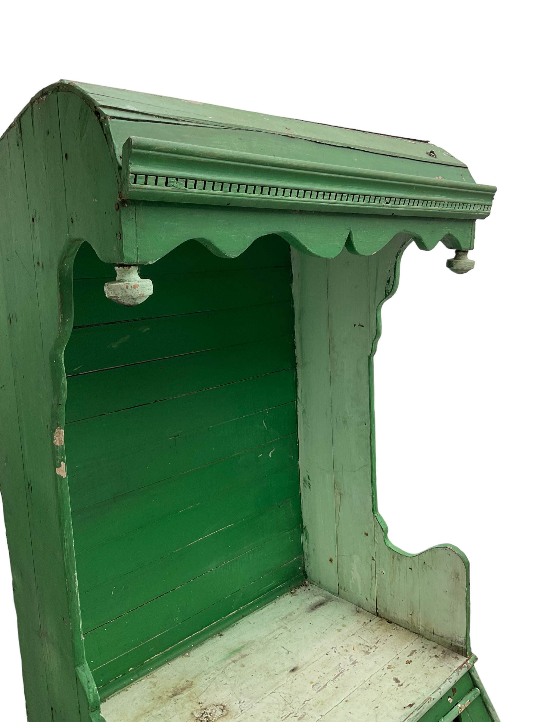 19th century painted pine hen coop settle, overhanging arched canape with dentil moulding and shaped edge, the panelled seat over a triangular platform base with removable hen-coop door, in green and white finish