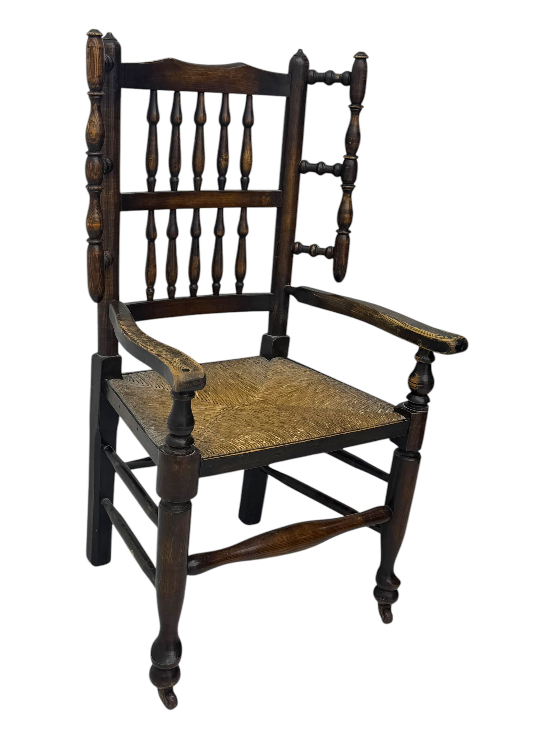 Early 19th century ash armchair, the back with winged spindles extending from a shaped top rail, above a splat of two rows of vertical spindles, with curved arms and a rush seat, raised on turned supports united by double stretchers terminating in castors