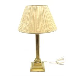 A brass Corinthian column table lamp, on stepped square base, including fitting H57cm, with pleated shade.