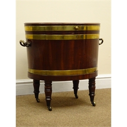  Regency mahogany brass bound oval wine cooler, hinged lid enclosing lead lined interior, brass side carry handles, the ring turned supports with brass sockets and castors, W62cm, H58cm, D43cm  