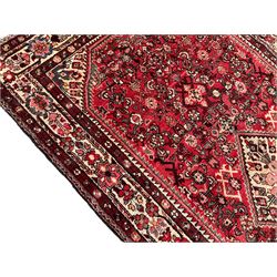 North West Persian Malayer crimson ground carpet, the central ivory lozenge medallion set in a field decorated with Herati motifs, with contrasting geometric spandrels, the multiband border decorated with repeating stylised plant motifs and flower heads