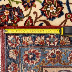 Central Persian Najafabad hand-knotted carpet, ivory field with an all-over scrolling floral design of palmettes, rosettes, and leafy vine work, enclosed by a wide floral main border flanked by multiple guard borders in madder red, indigo blue, green, and pale ochre, with cotton fringe ends 