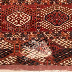 Persian Bokhara crimson ground rug, the field decorated with five rows of repeating Gul motifs with interspersed geometric design, enclosed by a guard band of further geometric-style Gul designs comprised of hook motifs