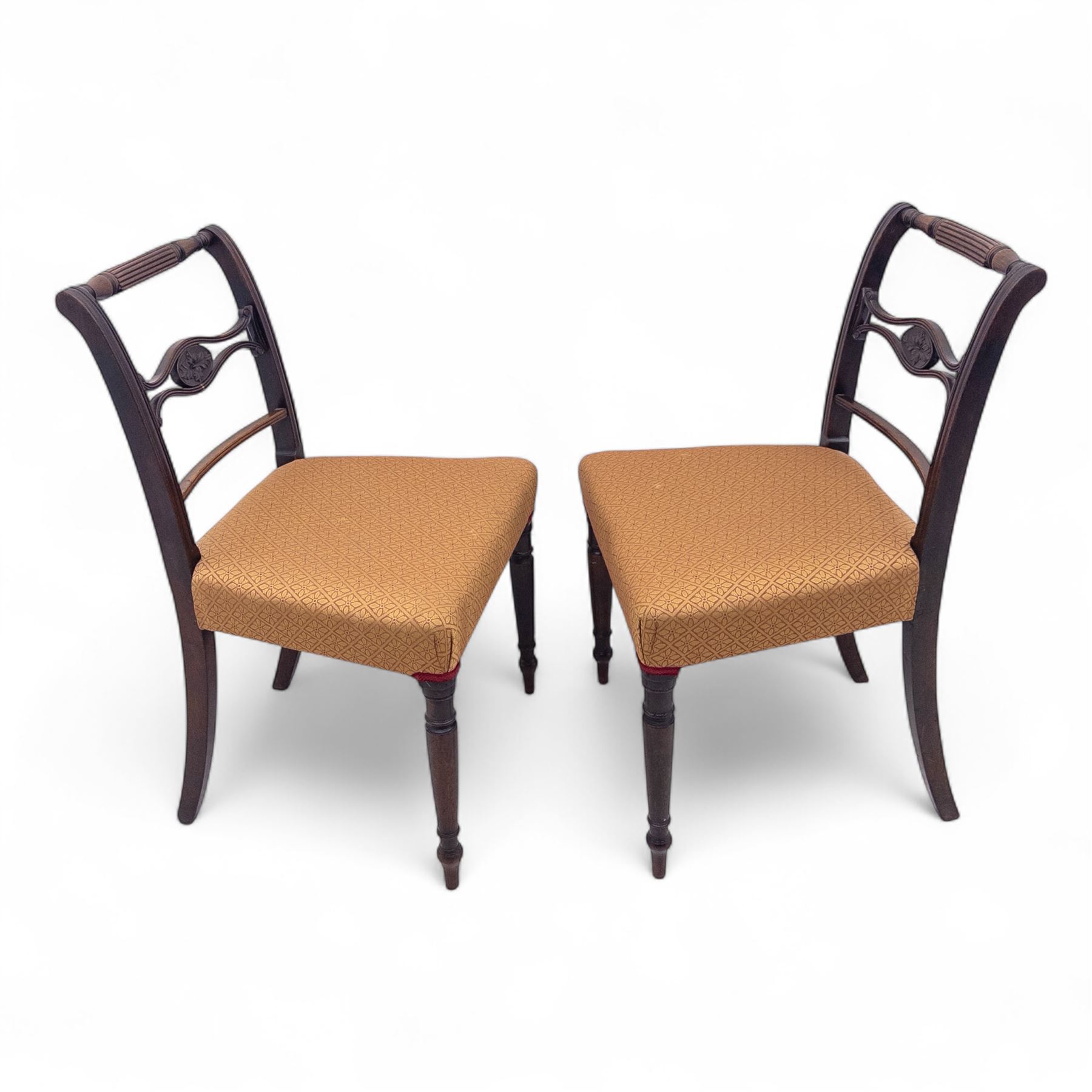 Pair of Regency mahogany side chairs, reeded bar backs centred by oval paterae, overstuffed seats upholstered in gold geometric patterned fabric, on turned tapering front supports 