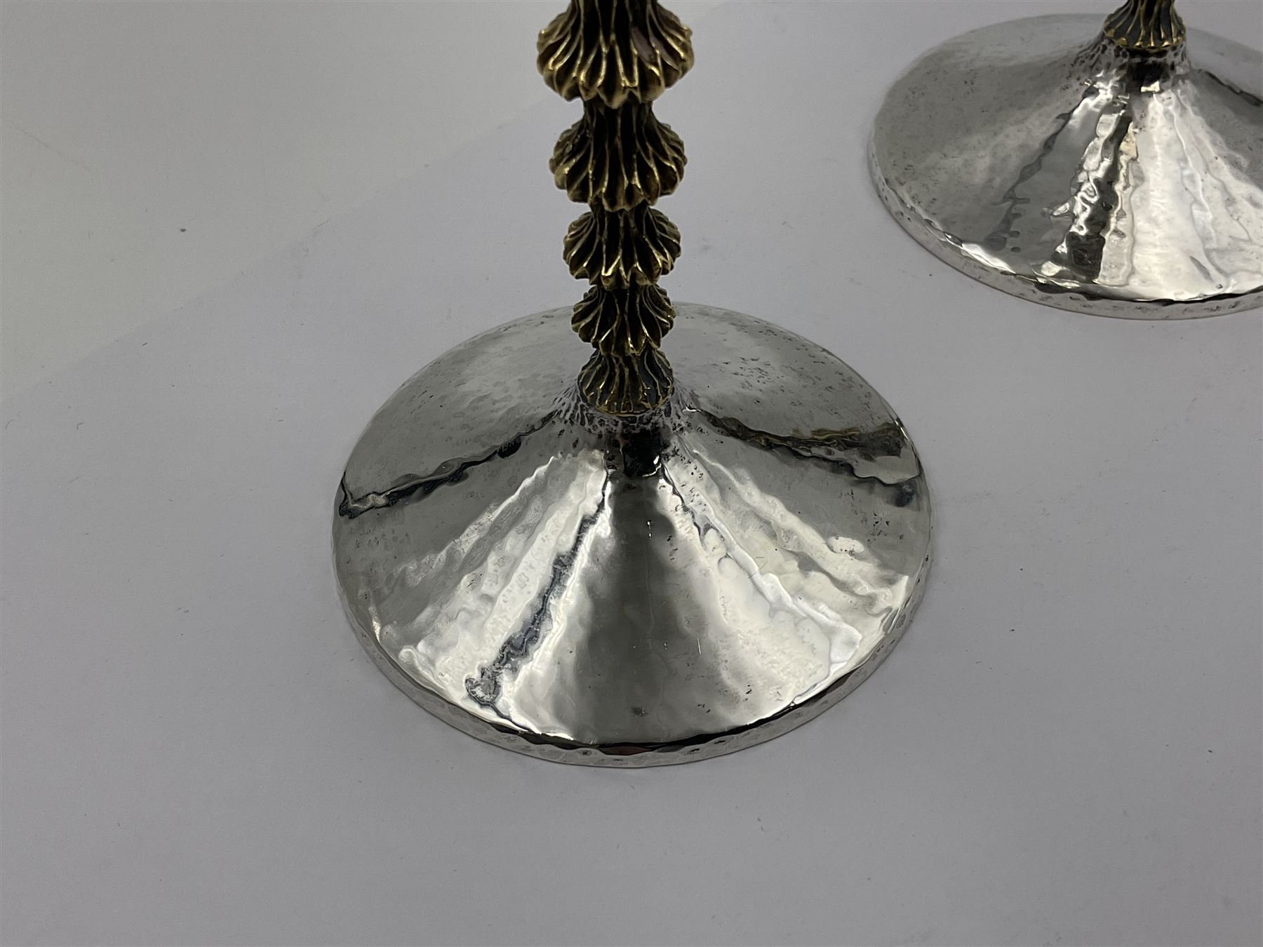 Pair of modern silver goblets by Stuart Devlin, the tapering cylindrical bowls each with spot hammered decoration and gilt interiors, the parcel gilt stems with signature textured detailing and six graduating knops, upon conforming spreading circular foot, hallmarked Stuart Devlin, London 1976, H17.7cm