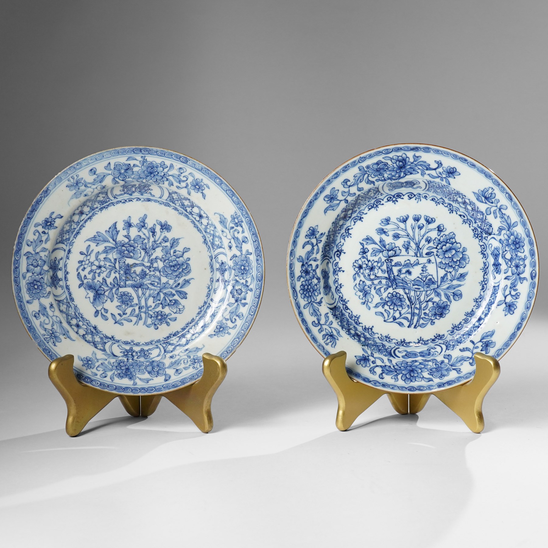 Pair of Chinese Kangxi period blue and white plates, painted in underglaze blue, decorated centrally with an unrolled handscroll revealing a shanshui landscape among foliage, D23cm (2)
