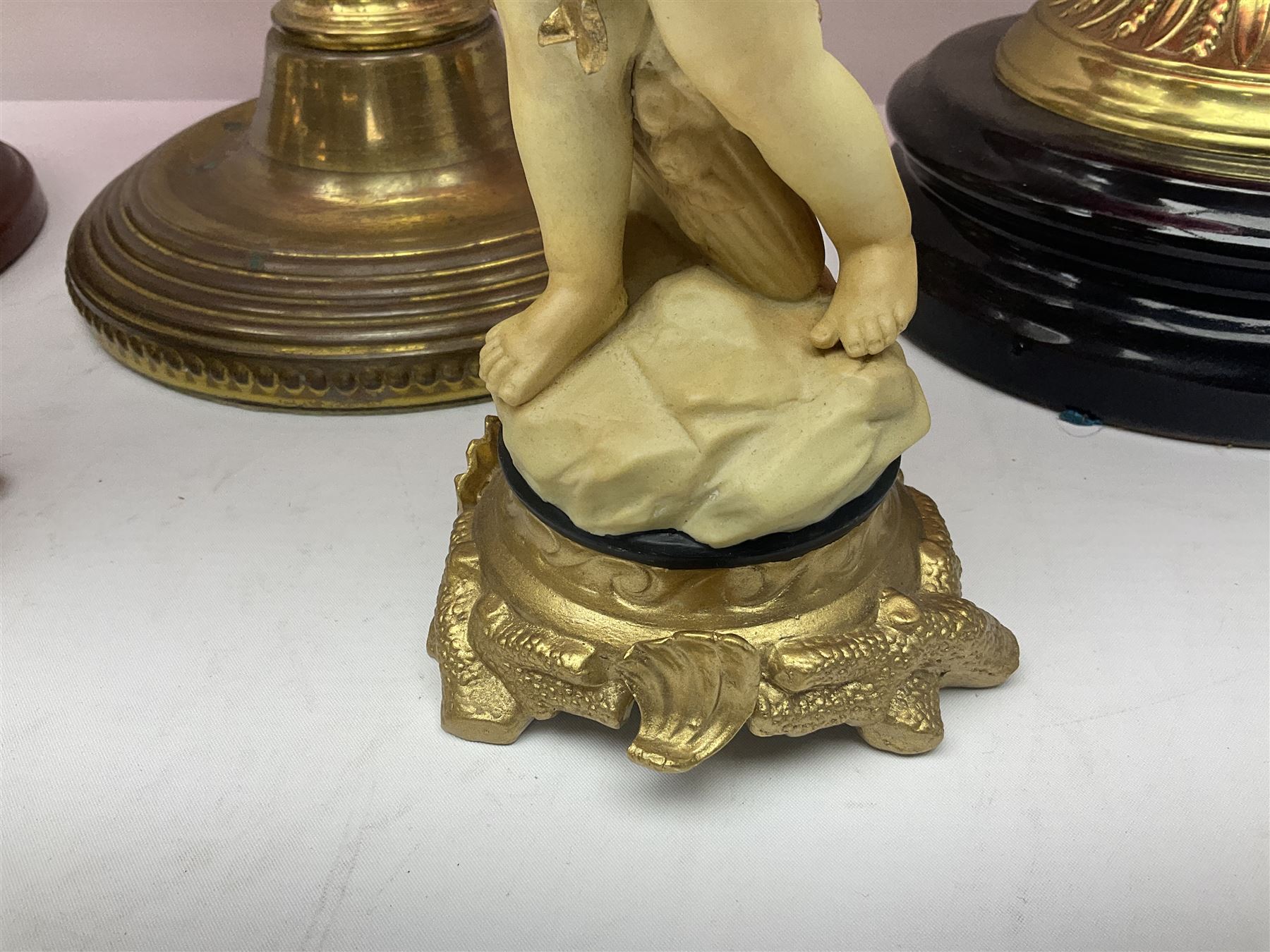 Victorian cast brass oil lamp, with fluted pink glass shade, together with two smaller brass oil lamps with pink shades and reservoirs and a pair of oil lamps, the bases modelled as putti, with pink glass reservoir  and frosted shades, tallest H70cm