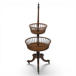 Regency style oak two-tier dumb waiter, with turned finial above central column support, two circular spindle-galleried basket tiers, raised on downswept tripod supports with brass caps and castors