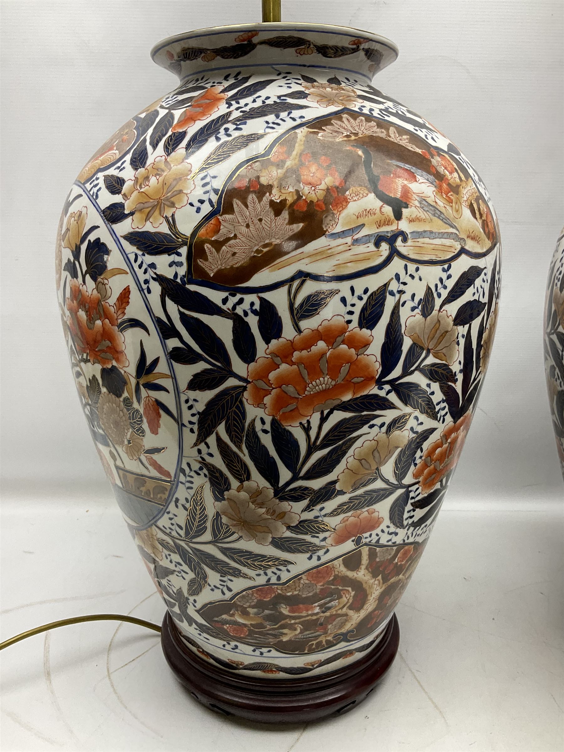 Pair of large and impressive 20th century Japanese Imari table lamps, each of ovoid form, decorated in the Imari palette with roundels containing flowering urns, and shaped panels of birds, set against a white ground decorated with blossoming peonies, lamp base (not including fixtures) H56.5cm overall including shade H89cm