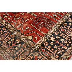 Anatolian crimson ground tribal rug, the field decorated with repeating geometric tree of life motifs with figural designs, the indigo guard band with stylised palmettes