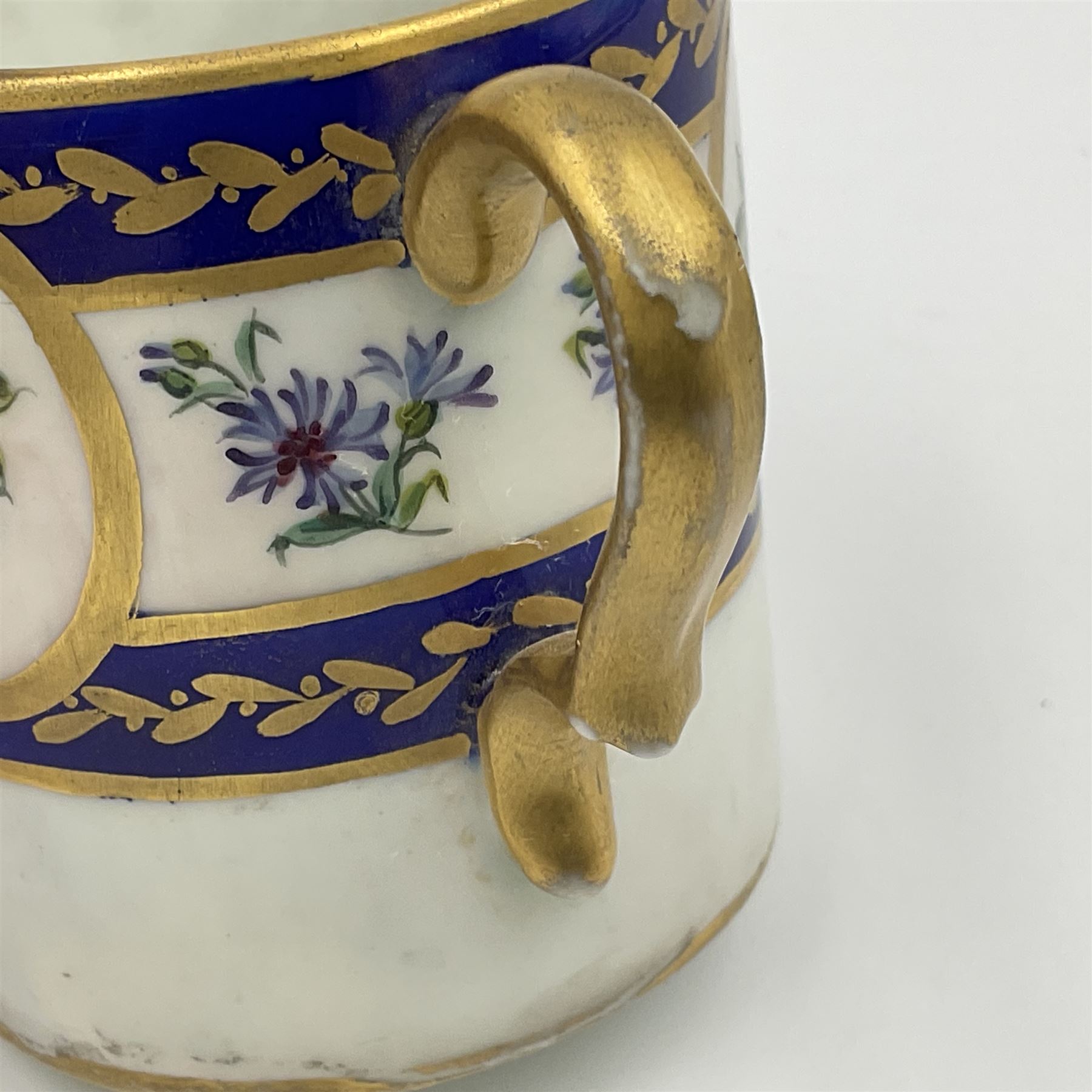 19th Sèvres style porcelain cup and saucer, the cup painted with a figural scene, against a scalloped border of scrolling floral swags on a blue ground, together with a Sèvres soft paste porcelain coffee can and saucer, painted with panels of exotic birds, roses and a border of cornflowers, LL monogram enclosing date letters H above painters mark, coffee can H6.5cm, saucer D13.5cm (2)