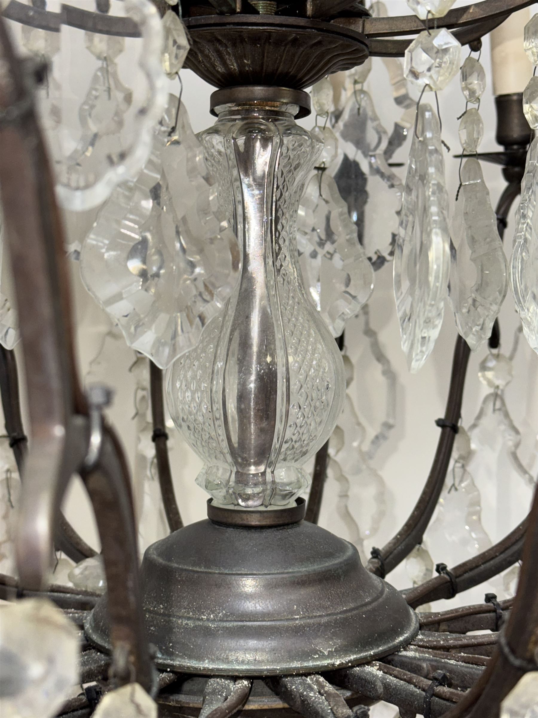 Early 20th century continental cut glass and metal chandelier, with sixteen candle style lights on a single tier of scrolled arms, hung with faceted glass drops and centred by a mould-blown and cut glass baluster stem, suspended from a ceiling rose and chain