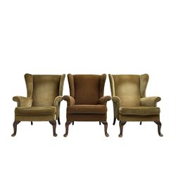 Parker Knoll - pair mid-20th century 'Penhurst' wingback armchairs, upholstered in dark olive green fabric, with foliate patterned textured seat cushions on cabriole front supports; with another in tan foliate patterned fabric (3)