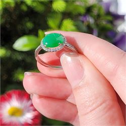 Platinum jadeite and diamond cluster ring, single oval cabochon cut jadeite of 2.20 carat, surrounded by round brilliant cut diamonds and diamond set shoulders, stamped Plat