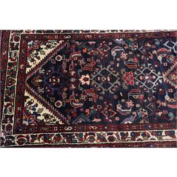 North West Persian Hamadan hand-knotted runner, indigo field with an all-over herati inspired lattice issuing from a central axis with stylized palmettes, rosettes and angular vinery, enclosed by stepped triangular spandrels with ivory reserves, broad ivory main border of stylized flowers and geometric devices, flanked by reciprocal guard stripes, cotton fringe ends 