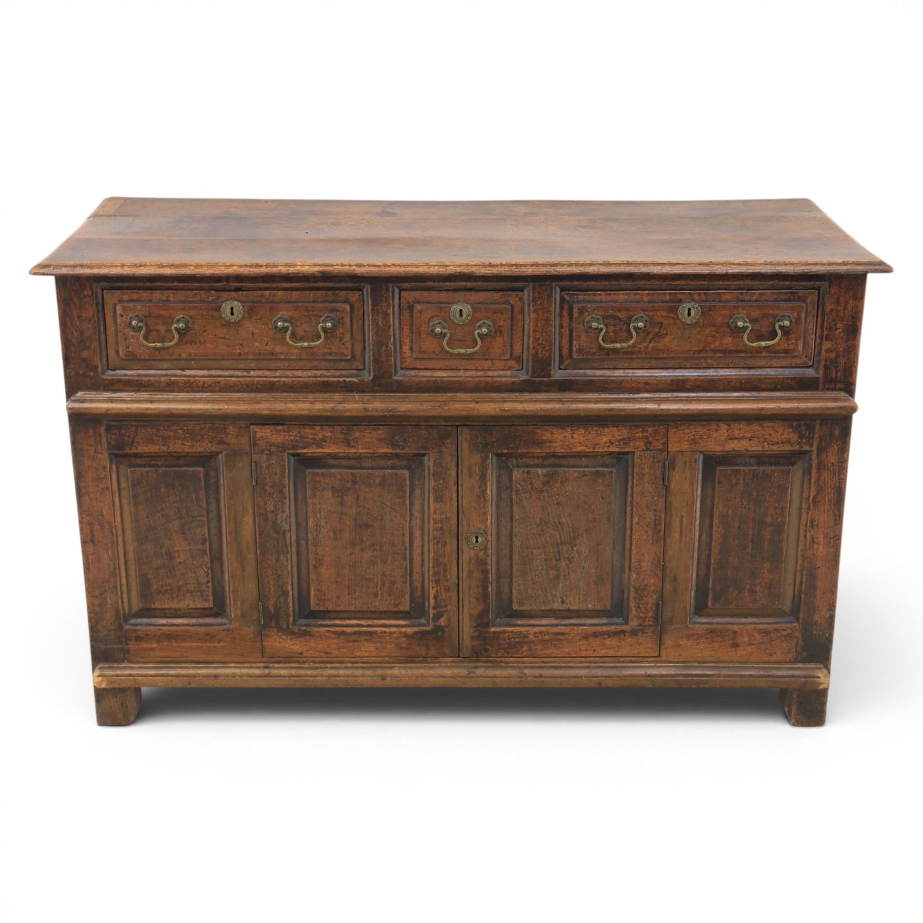 George III oak dresser base, rectangular top with moulded edge, three fielded panelled drawers with brass swan neck handles, over four fielded panelled front with the central two cupboard doors, raised on stile supports