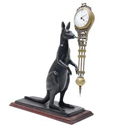  20th century-8-day Marsupial mystery clock with a cast brass patinated model of a standing Kangaroo on a wooden base, with a swinging compound pendulum resting on two steel pivots, white dial with Arabic numerals, minute track and steel spade hands, wound and set from the rear.
