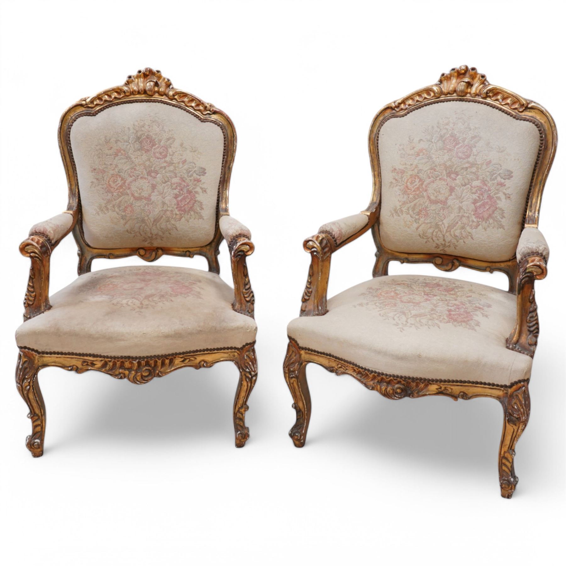 Pair of Louis XV design gilt framed armchairs, shaped cresting rail decorated with shells and foliage, upholstered in floral pattern fabric, on shell carved cabriole front supports 