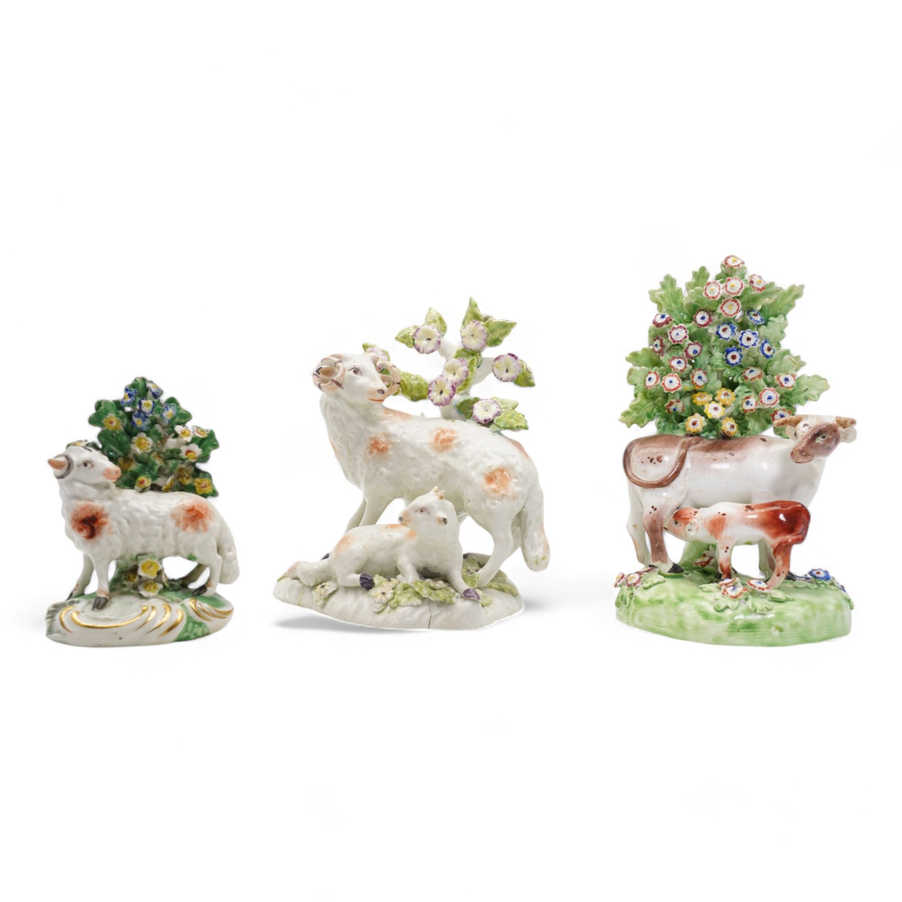 Two 18th century Derby porcelain groups modelled as a ram standing before bocage above a recumbent lamb, upon flower encrusted base, H15cm and two further Derby figures modelled as a ram and cow and calf (3)