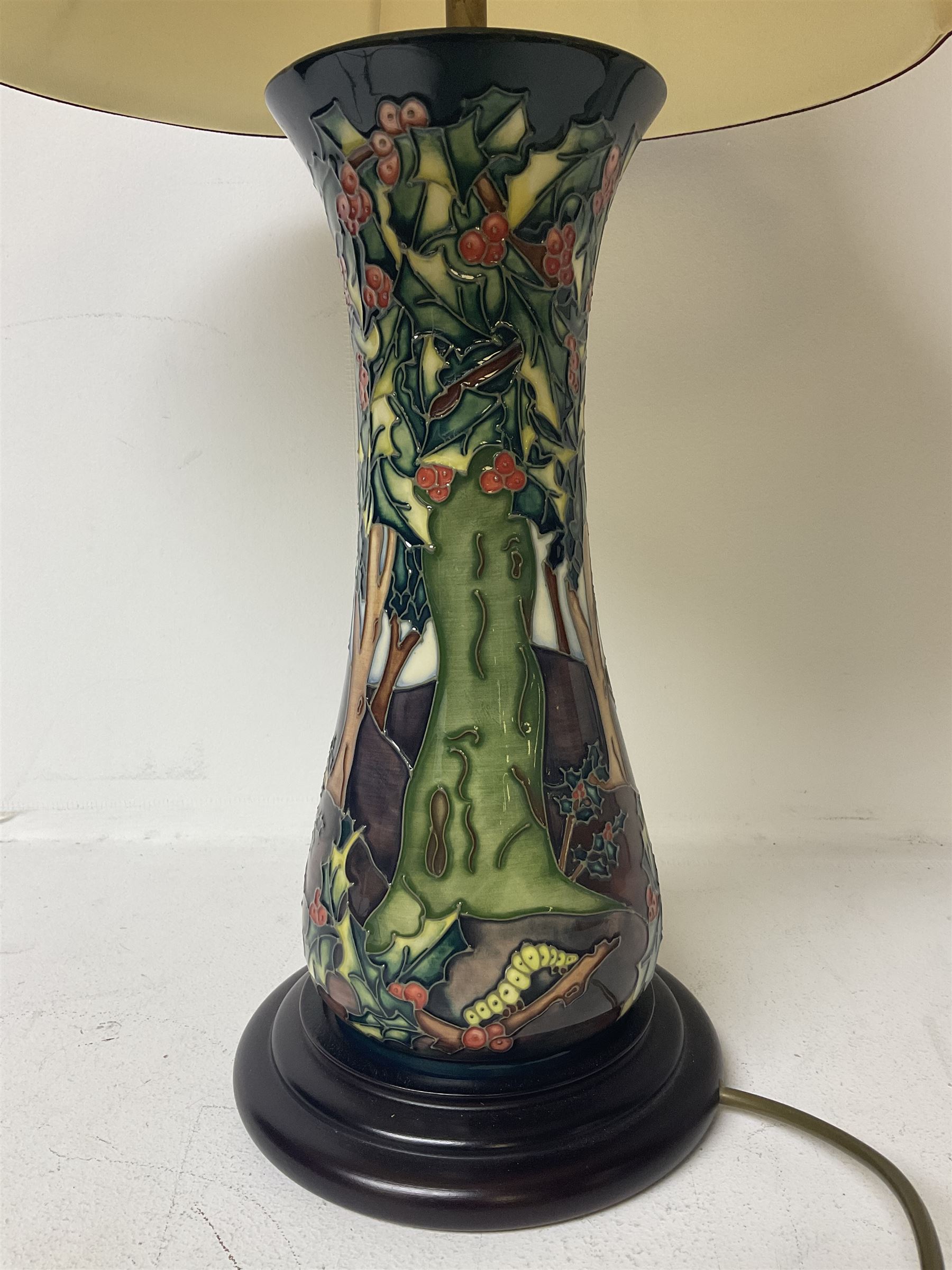 Moorcroft table lamp, of waisted form, decorated in the Holly Hatch pattern, on wooden plinth, with accompanying cream shade of lobed form, with piped detail, H33cm (excluding fitting)