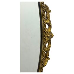 Oval gilt wall mirror, with bevelled edge plate within a moulded frame cast with acanthus scrolls and foliate decoration, pierced cartouche crest and apron, flanked by scrollwork handles