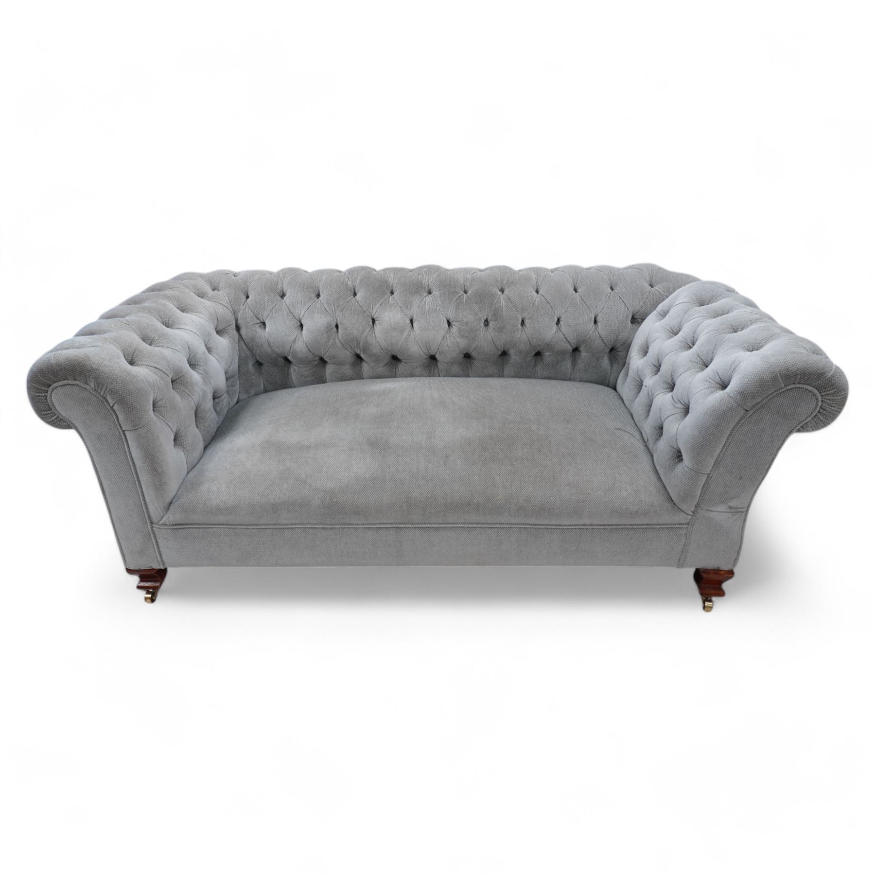 Early 20th century Chesterfield drop-arm two-seat settee, traditional shape with rolled arms and back, upholstered in buttoned pale blue fabric, on ogee block feet with brass castors 