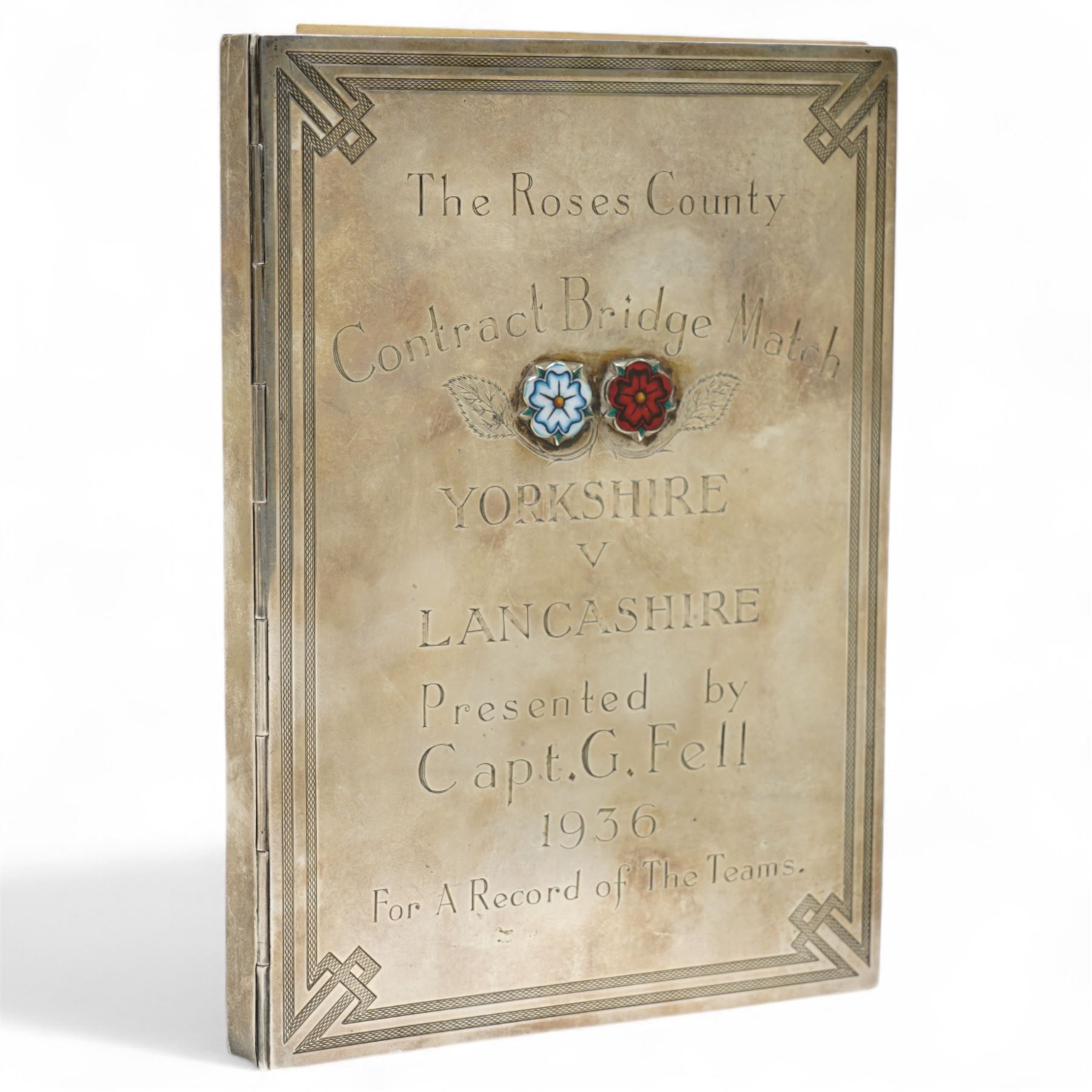 'The Roses County Contract Bridge Match, Yorkshire V Lancashire presented by Capt. G Fell 1936 for a record of the teams' - A silver booklet decorated with enamel roses containing hand drawn lists of the teams 1936 together with other team lists 1955-1984 15cm x 10cm Birmingham 1936 Maker S Blackensee & Son Ltd