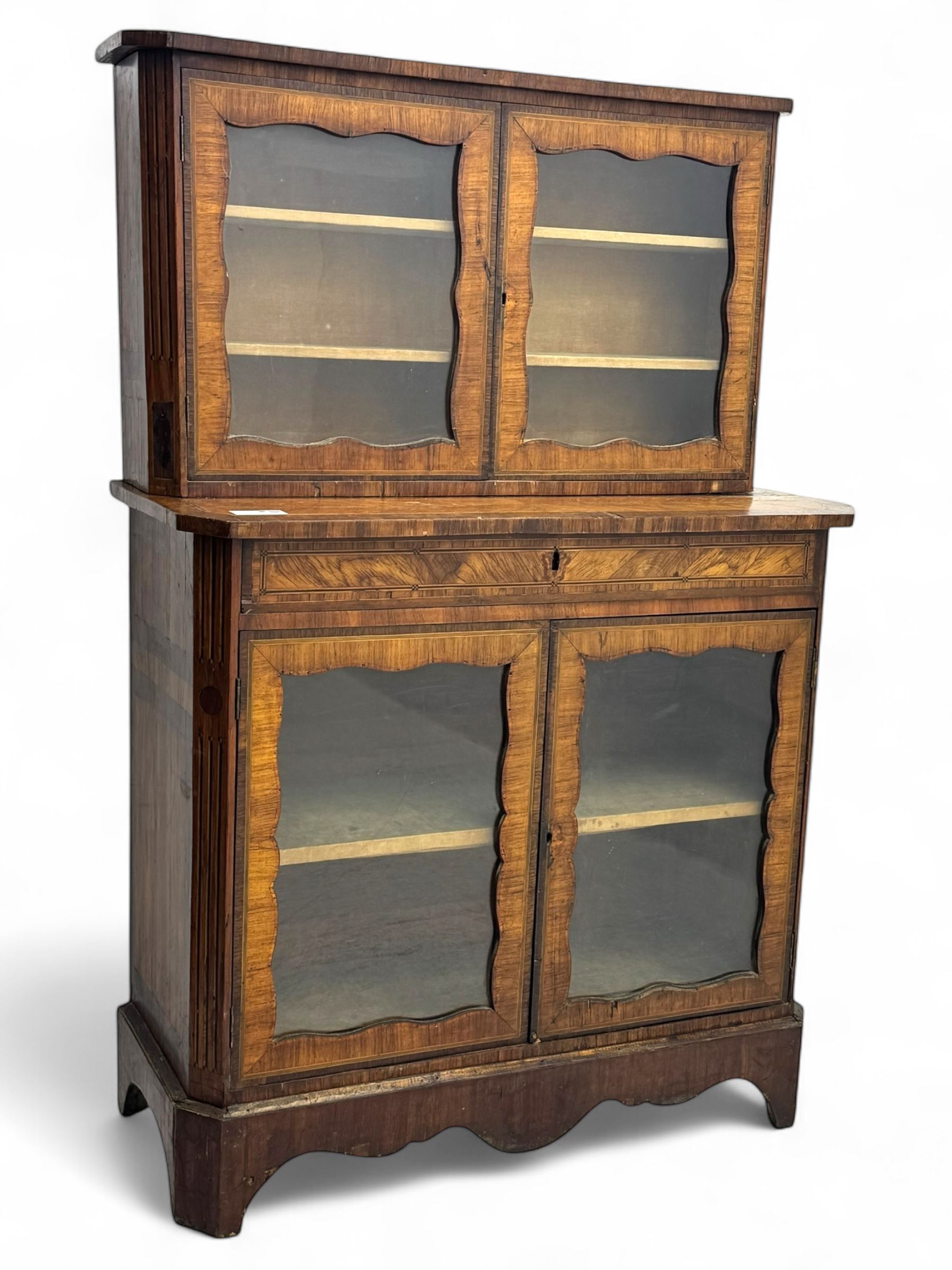 Late 19th century continental display cabinet, the upper section is glazed with twin doors with two upholster shelves, over a lower section with single draw above two glazed cupboard doors on shaped bracket feet