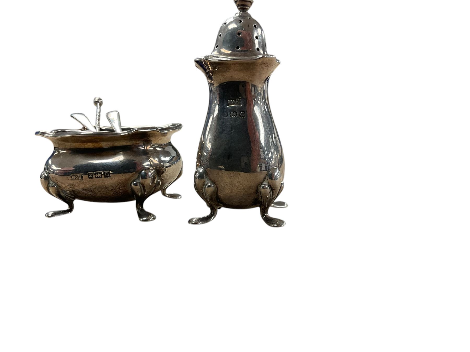 1920s silver three piece part cruet set, comprising pepper shakers, open salt with blue glass liner and a mustard pot, all upon four pad feet, hallmarked White & Hawkins, Birmingham,  , with three silver salt spoons, hallmarked 