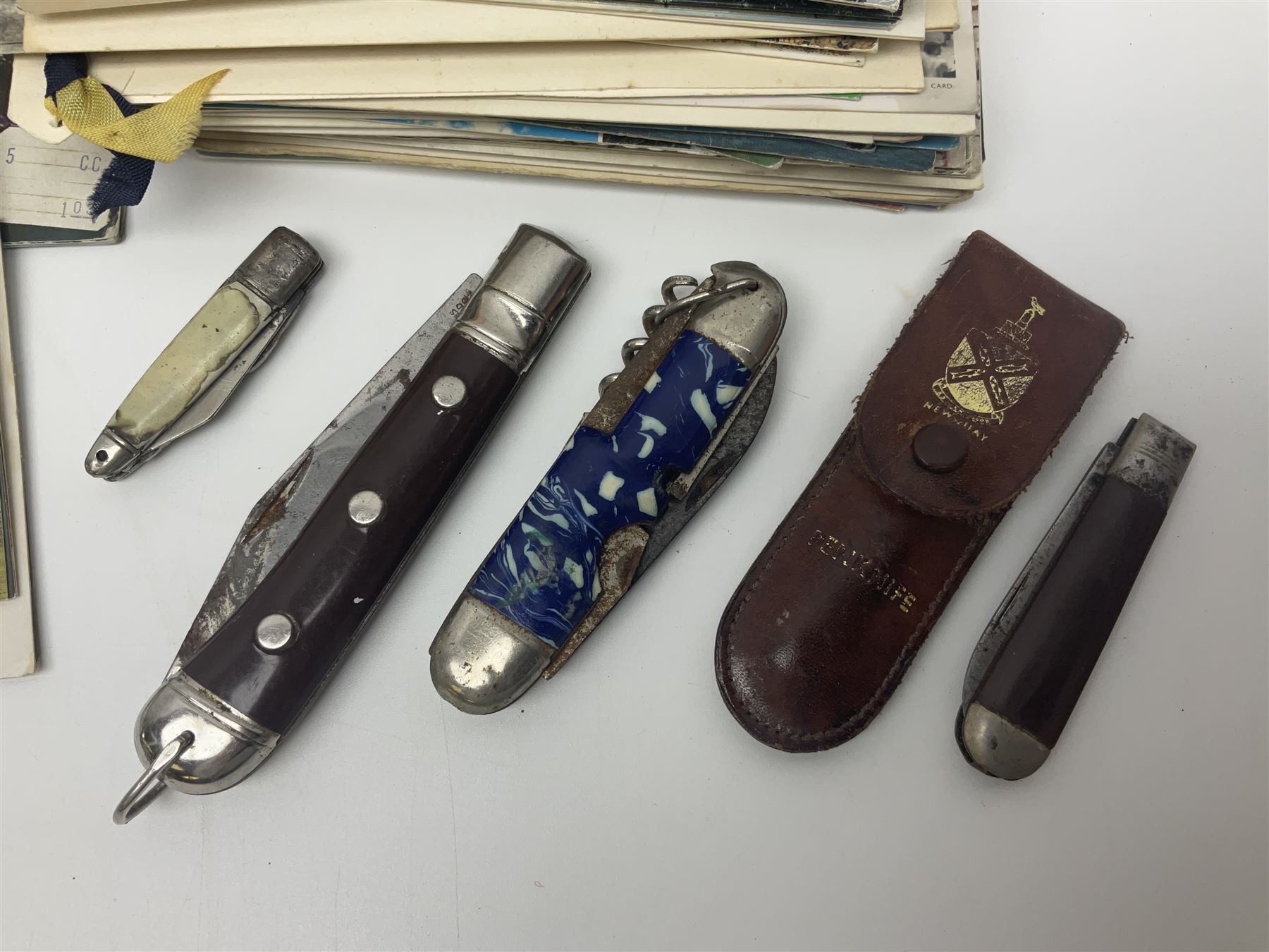Seven pen knives, two lighters, including one Ronson example and a collection of postcards