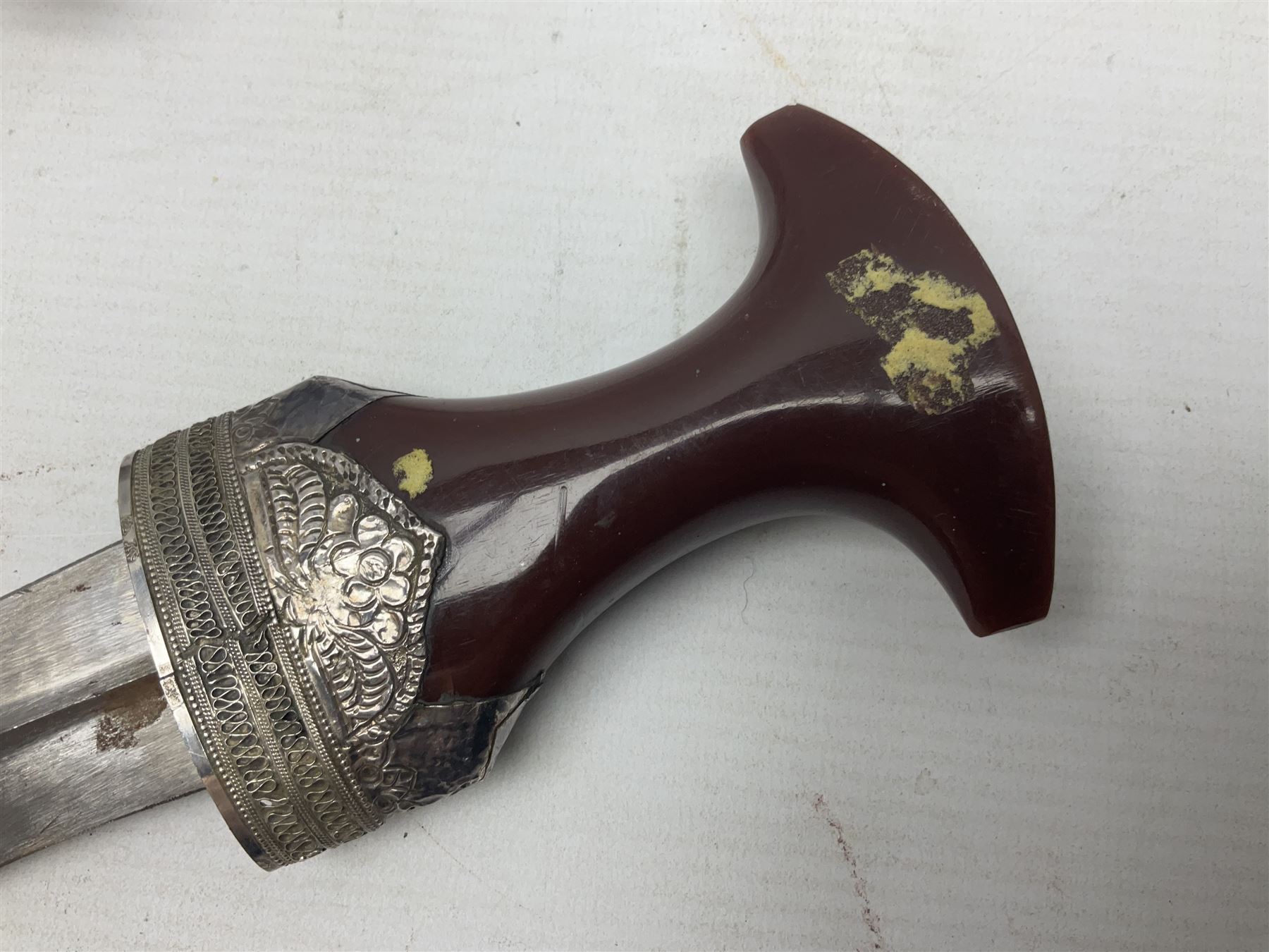 Omani Khanjar dagger, the 12.5cm curved blade with pronounced medial rib to either side, waisted horn style hilt with dome shaped pommel and inlaid pique work; in an intricately filigree decorated white metal scabbard with rings woven into the belt mount L25cm overall