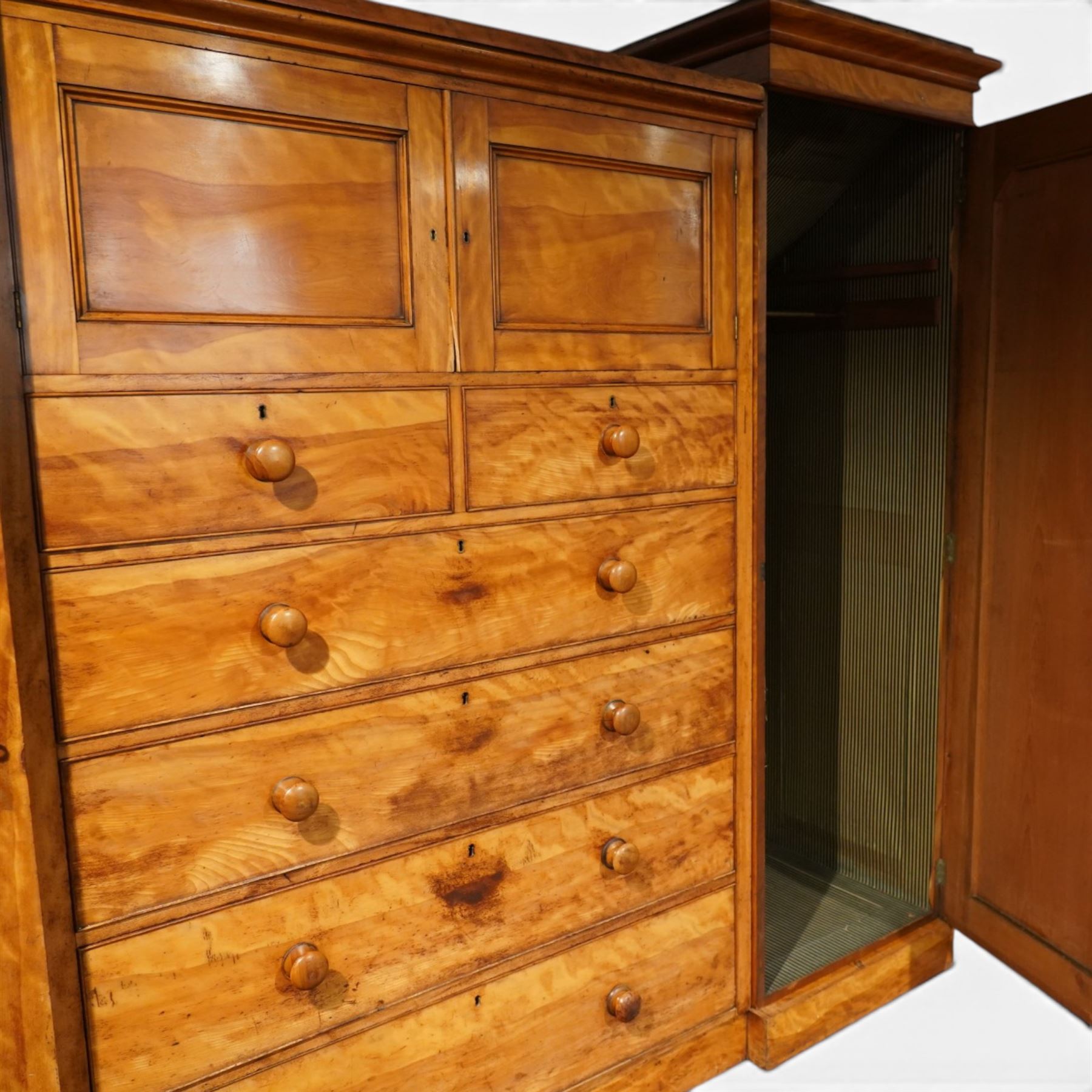Victorian satinwood reverse breakfront triple wardrobe, projecting moulded cornice over twin full-length panelled cupboard doors flanking central linen press section, fitted with two cupboard doors above two short and four long drawers, turned wooden handles and moulded plinth base