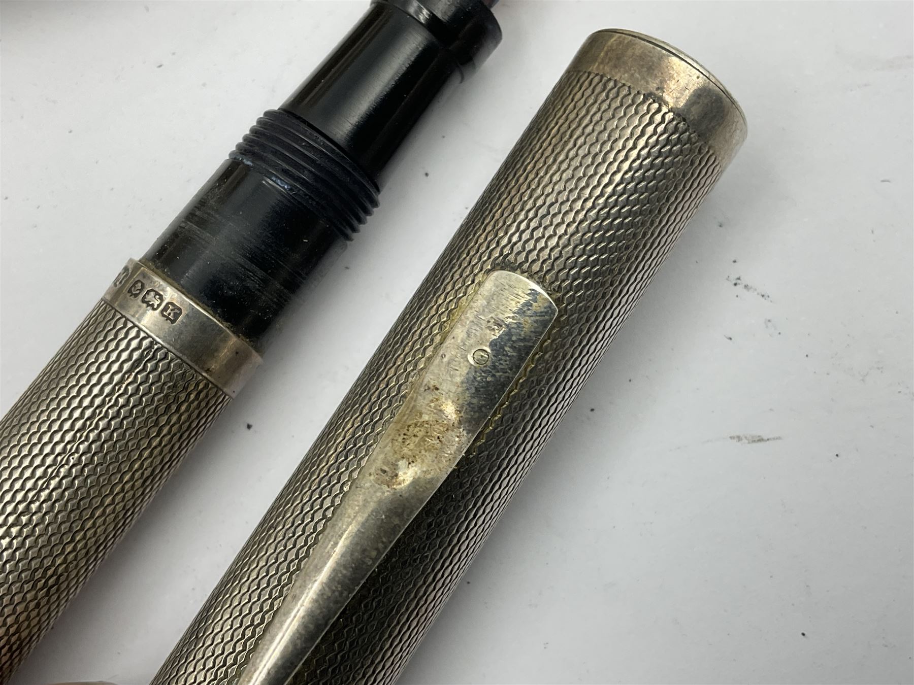 Three parker fountain pens, one example with 14ct gold plated cap and personal engraving, in Parker 51 box, together with a silver Sampson Mordan Everpoint propelling pencil with personal engraving and a silver cased fountain pen with 14ct gold nib and a souvenir bronze Dollfus-Mieg medallion, awarded to John G Sedorski, in fitted case 