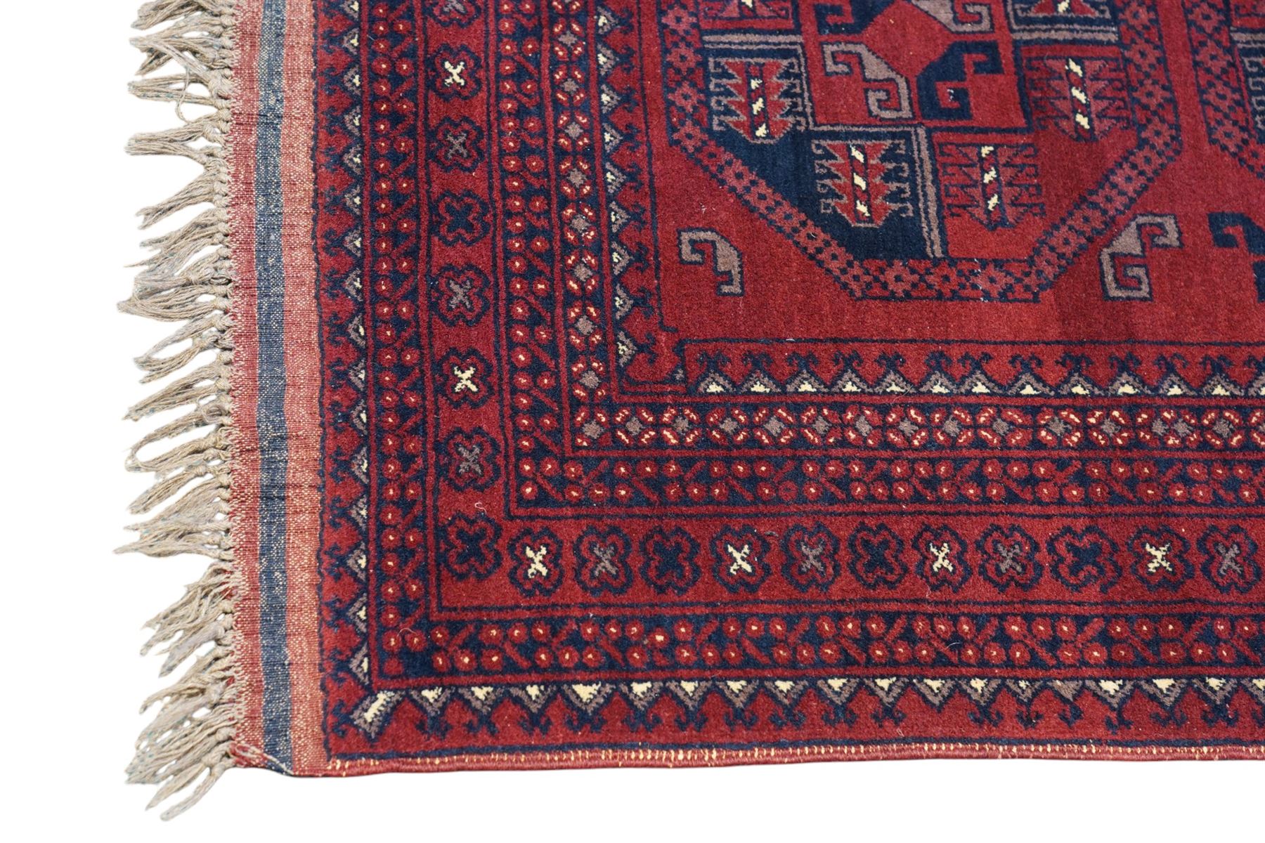 Afghan red ground Bokhara rug, the field decorated with two rows of large Gul motifs, within geometric pattern borders 