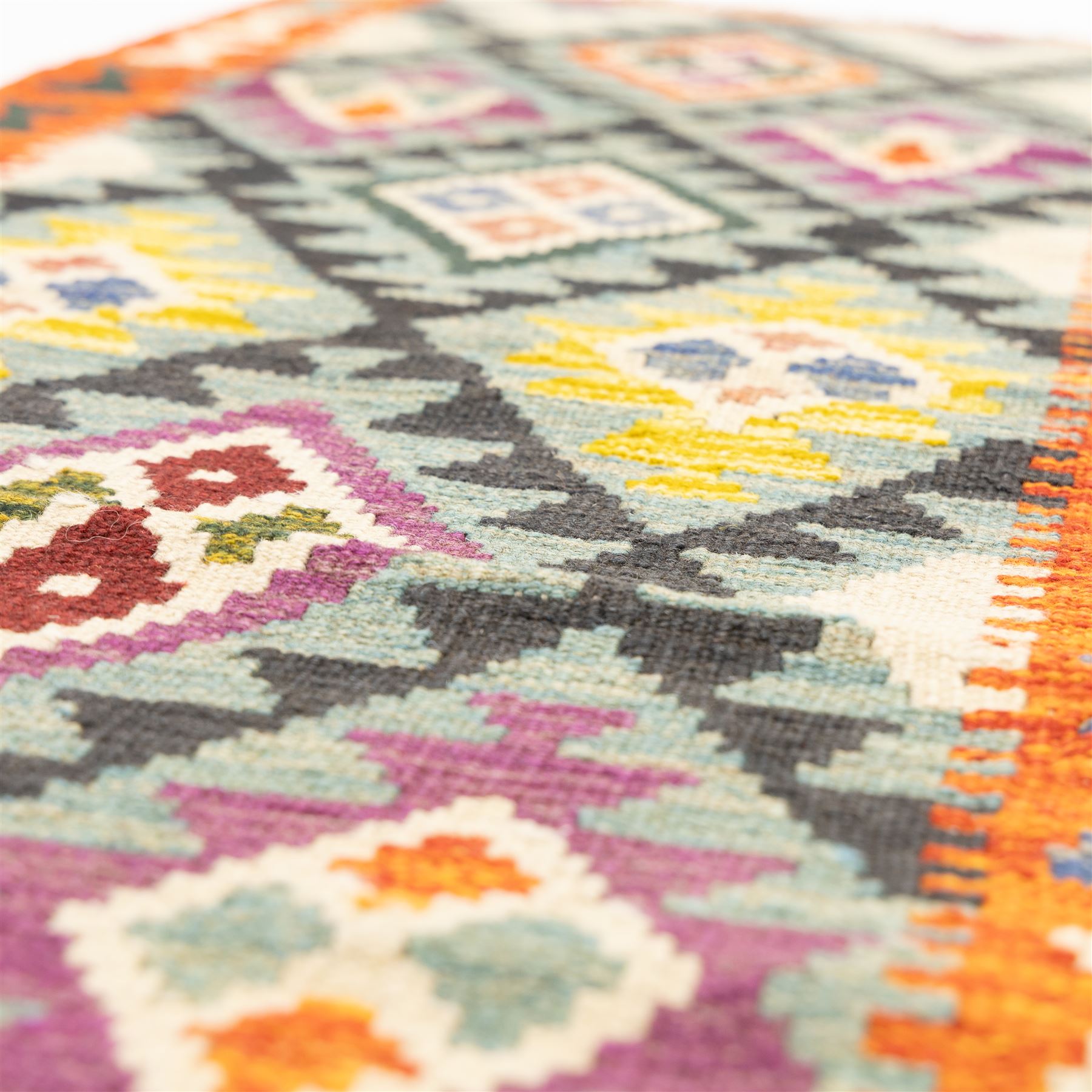 Chobi flatweave kilim runner with a repeating stepped diamond medallion design in live green, rust, teal, purple, and ivory, framed by chevron and geometric borders